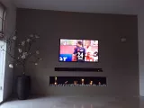 Grijze wand met TV en sfeerhaard